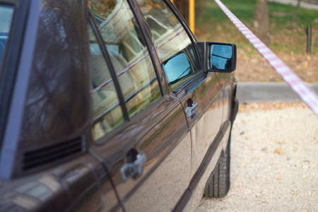The car is parked at the red tape. Rearview mirror by the car. An old car is parked in the street.の写真素材