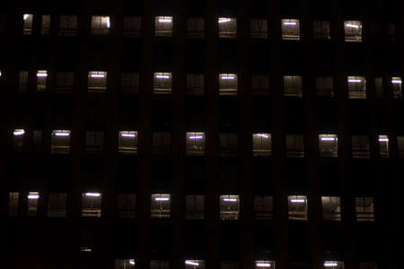 Windows in the dark. Many windows are burning in the building. A background of repeating architectural elements. Window background.の写真素材