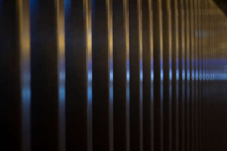 Ribbed fence. The texture of the metal fence. Background of a steel surface with orange and blue hues. A repeating element with gradual defocusing.の写真素材