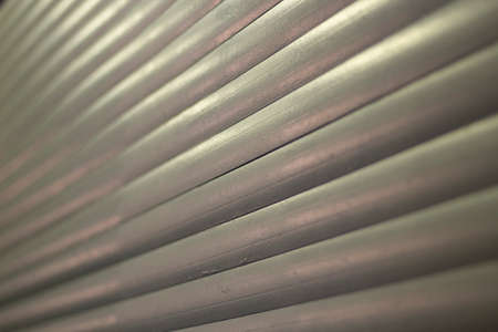Ribbed texture in evening light. The plastic surface of the blinds. Gray repeating slats shot with open aperture. Simple background.の写真素材