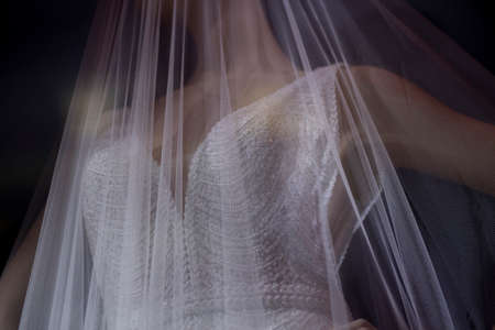 Wedding veil on a mannequin. Transparent white cloth on a plastic mannequin. Demonstration of the wedding accessory. Shooting in the dark with lightweight fabric.の写真素材