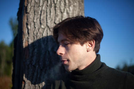 Portrait of a guy in the forest. The face of a young man on the streets. Short-haired male. The guy in the sunshine.の写真素材