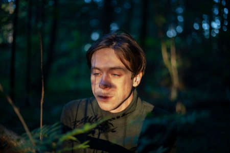 Portrait of a guy in the forest. The face of a young man on the streets. Short-haired male. The guy in the sunshine.の写真素材