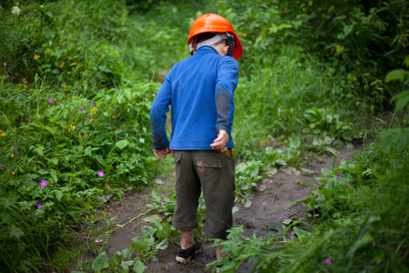 Child in the forest in an orange construction helmet. The boy's walk in an unknown place. Lost child...