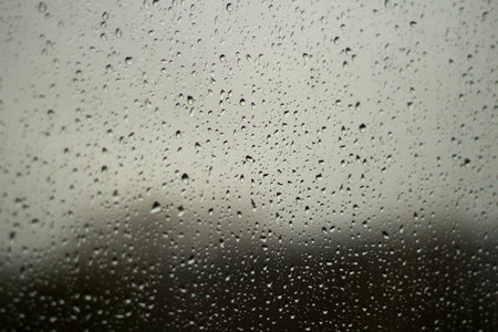 Raindrops on glass. Wet weather outside the window. Texture of drops on a transparent surface. It's...