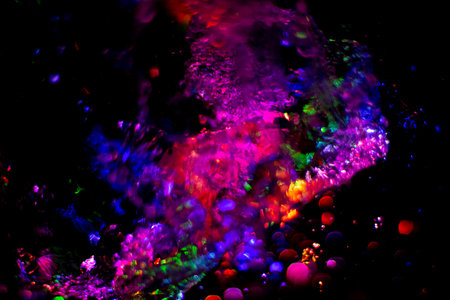 Colored water texture. Splashes of water lit in different colors. Close-up shot of water from the...