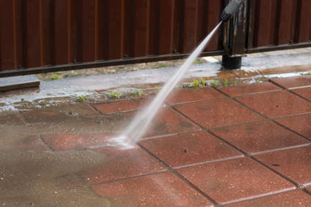 Washes the treadmill with a jet of water. The man removes the dirt from the path. Cleaning the fence and sidewalk from dust.の写真素材