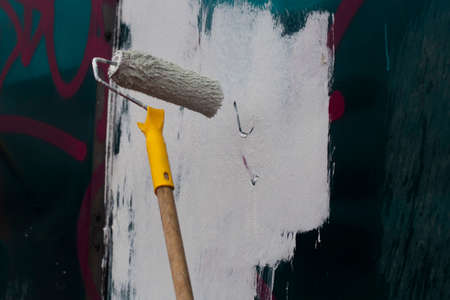 Paints the graffiti with a roller. The molar paints the wall with white paint. A tool for fast surface painting.の写真素材