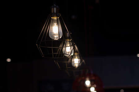 Stylish lamps hang in the dark. The lamps are on. A row of lamps in a cafe.の写真素材