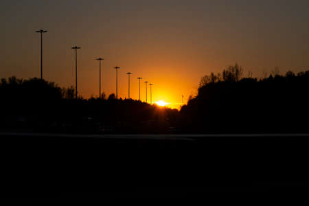 Sunset over the road. Evening on the highway. The sun sets over the horizon. Sunset colors in the atmosphere.の写真素材