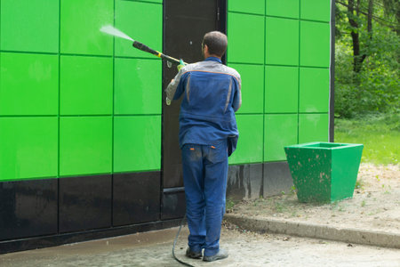 Hose the wall. Washing from the dirt of the fence. The mud is removed by the pressure of the water....