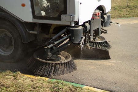 The sweeper is sweeping the asphalt. Cleaning the path with a cleaning vehicle. Cleaning the area from dust.の写真素材
