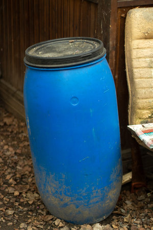 Blue storage barrel. The oil barrel is on the ground. The use of a plastic barrel on the farm.