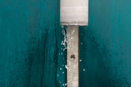 Water is pouring out of the drain. Drain pipe on the street. Drainage of rainwater from the roof.の写真素材
