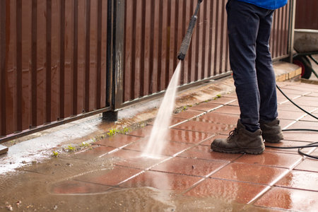 Washes the treadmill with a jet of water. The man removes the dirt from the path. Cleaning the fence and sidewalk from dust.の写真素材