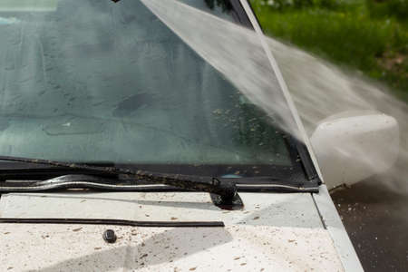 Washing the windshield from dirt. The car is washed by the pressure of the walls. Caring for vehicles after a muddy road.の写真素材
