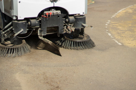 The sweeper is sweeping the asphalt. Cleaning the path with a cleaning vehicle. Cleaning the area from dust.の写真素材
