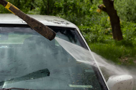 Washing the windshield from dirt. The car is washed by the pressure of the walls. Caring for vehicles after a muddy road.の写真素材