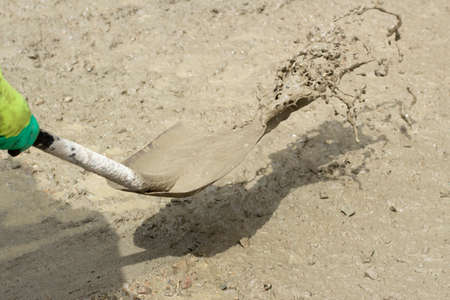 Shovel with sand. Throws sand with a shovel. Work at a construction site. Removing dirt from the road.の写真素材