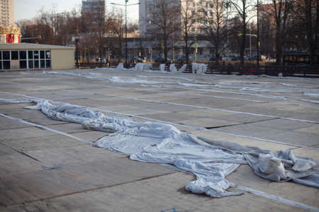 Ice skating rink cleaning in summer. A large cloth is lying in the stadium. The former ice skating rink is closed. Analysis of the tribune in the square.の写真素材