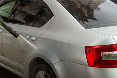 The car is washed at the car wash. Washing the car from dirt. High pressure water spraying equipment for washing car surfaces.の写真素材
