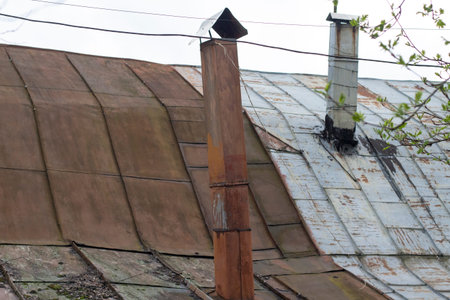 Chimney on the house. Roof of an old house. The worn-out roof of the garden house. Tuba from the roof.の写真素材
