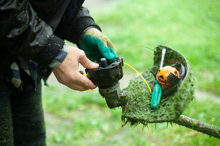 Lawn mower repair. Saodnik's tool. The lawn mower is defective. Installing a string for cutting grass.の写真素材