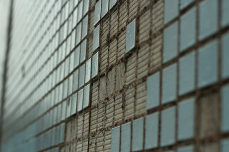 Broken tiles on the wall. The texture of the tiles on the building. Tile squares were crumbling.