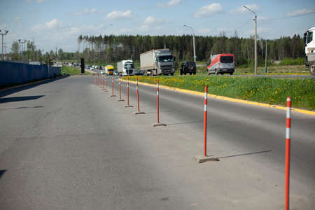 Red parking stops. Fencing the carriageway from cars. Bright orange parking warning posts. The highway is separated from the truck parking lot.の写真素材