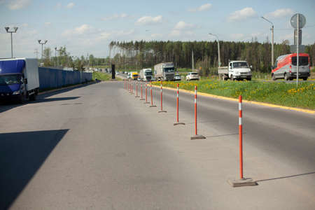 Red parking stops. Fencing the carriageway from cars. Bright orange parking warning posts. The highway is separated from the truck parking lot.の写真素材