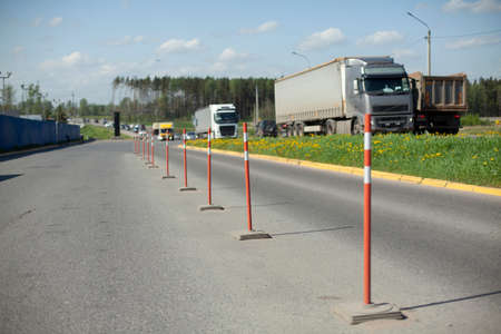 Red parking stops. Fencing the carriageway from cars. Bright orange parking warning posts. The highway is separated from the truck parking lot.の写真素材