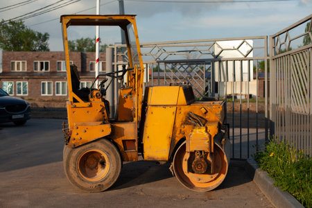 Bulldozer for paving yellow asphalt. Heavy machinery for road repair. Working car in the parking...