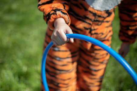 The girl is holding a hoop. The animator plays with the children with a hoop. Blue sports hoop in the hand of a teenager. A girl dressed in a tiger squeezes a circle in her hand.の写真素材