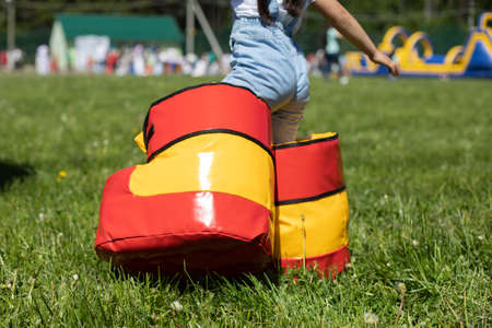 Child in inflatable boots. The kindergartner plays at the party. Boots for funny walking. Uncomfortable shoes on the child. Preschooler game on the green lawn.の写真素材