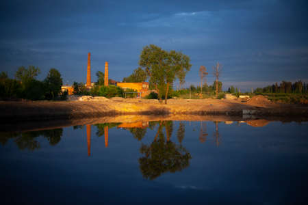 A pond excavated in the city. Water and shore. The lake at sunset. The land around the pond.の写真素材