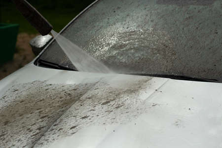 Car wash. The car is washed under the pressure of a jet of water. Using a water spray to wash off dirt from the surface of the car.の写真素材