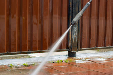 Washes the treadmill with a jet of water. The man removes the dirt from the path. Cleaning the fence and sidewalk from dust.の写真素材