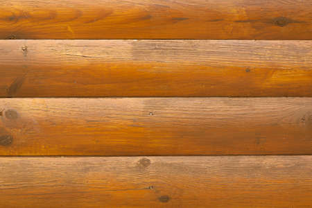 The texture of the logs. The wall is made of wood. Yellow colors in lacquered wood. Country house made of felled wood.の写真素材