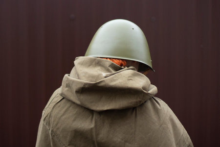 A soldier in a helmet from the back. Old Soviet military uniform. A cloak on a soldier.の写真素材