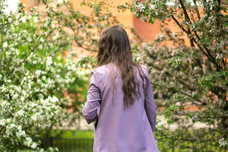 The girl in the lilac jacket. A woman walks in the park. The girl from the back.の写真素材