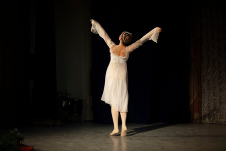 The girl is dancing on stage in a white dress. The artist is performing. Beautiful dance moves....