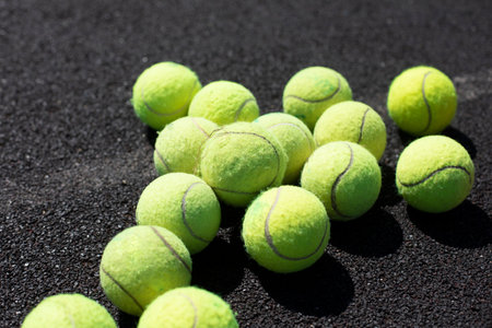 Tennis balls. The balls lie on the surface of the playground. Playing tennis with a ball. Green soft balls for racket strikes.の写真素材