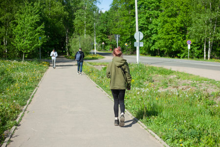The girl walks down the street. People on the pedestrian road. Park path to the city. People without faces.の写真素材