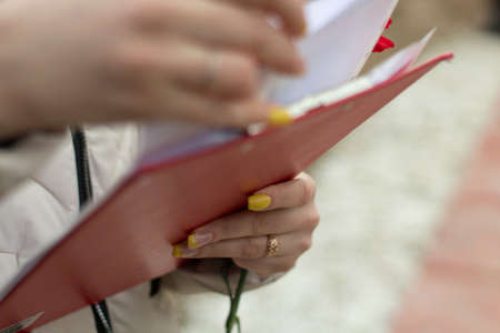 The secretary holds a tablet with papers. The girl is holding an office paper with text. Studying documents. Printed documents are crossed by hand.の写真素材