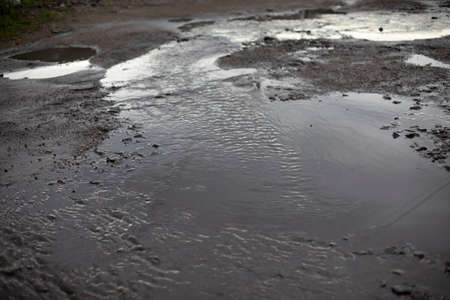 Dirty puddle on the road. Drain the water on the roadway. Flooding of the road after the rain.の写真素材