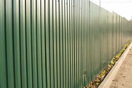 Steel fence. The fence is high on the street. Solid barrier.の写真素材