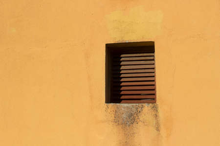 The ventilation window outside the building. The duct lattice. The removal of warm air through ventilation. Yellow wall and brown grille.の写真素材
