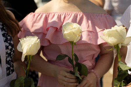 Flowers in the hands of the girls. The woman is holding a rose. Roses in the hands of schoolgirls.の写真素材