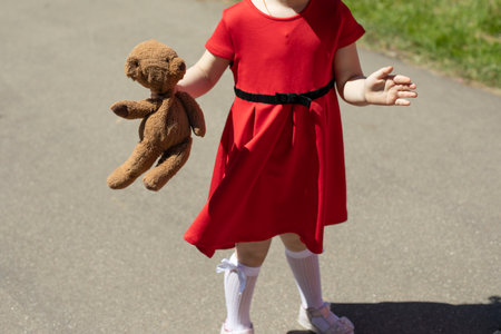 Child with a teddy bear. Girl with a soft toy. Child at the party. A girl in a red dress on the street.の写真素材