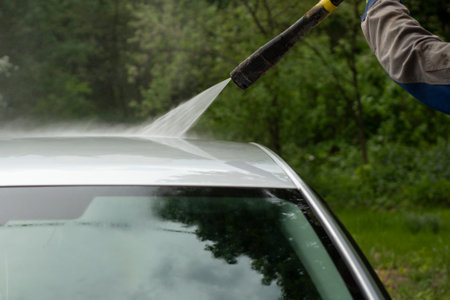 The car is washed at the car wash. Washing the car from dirt. High pressure water spraying equipment for washing car surfaces.の写真素材